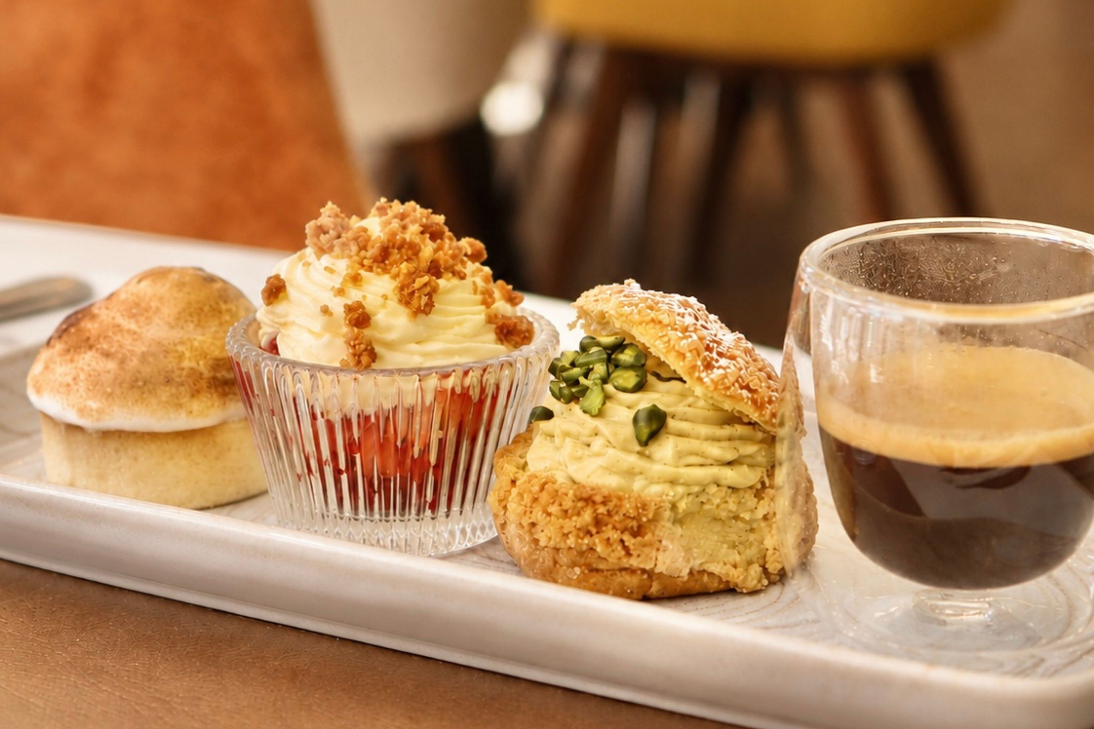 Una bandeja con tres pasteles y una taza de café.