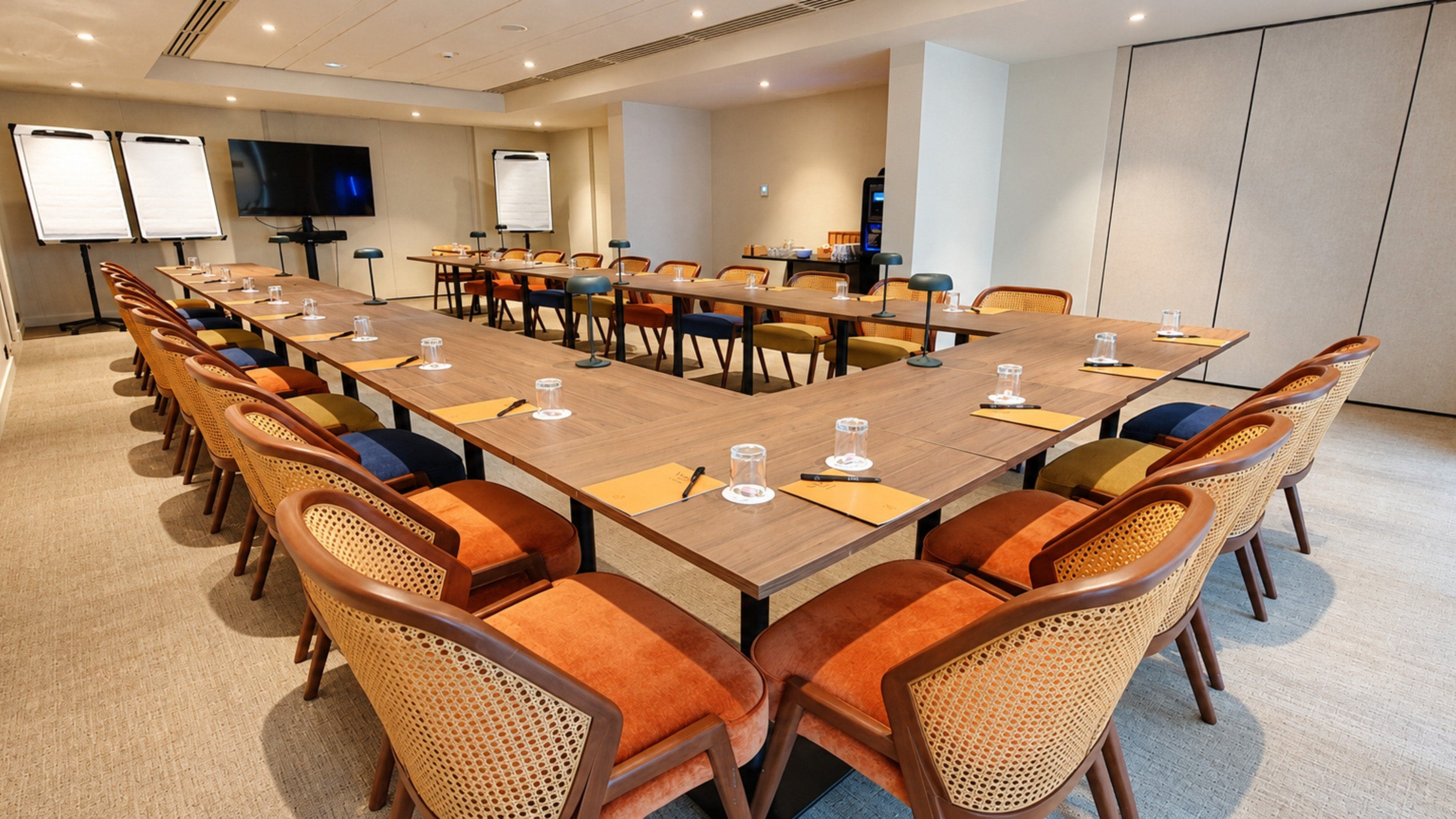 A conference room with a long table, multiple chairs, a television, and whiteboards.