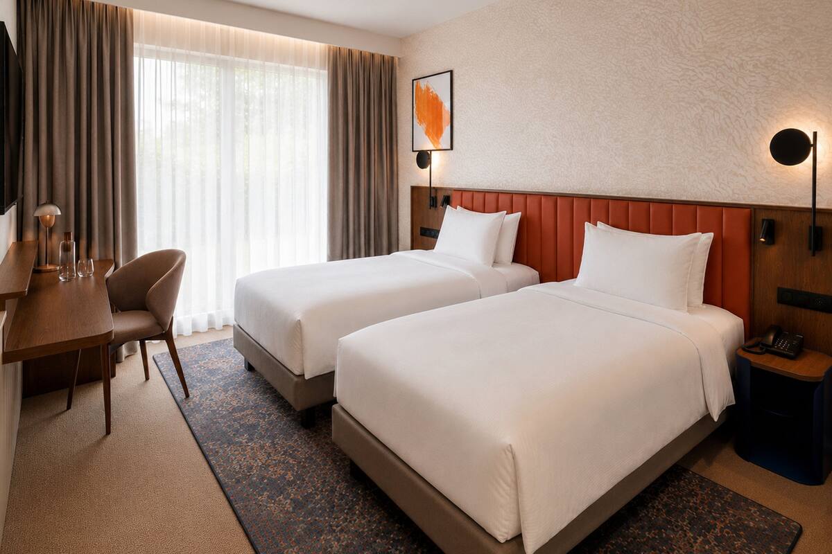 Ein Hotelzimmer mit zwei Betten, einem Schreibtisch, einem Stuhl, einer Lampe und einem Telefon.