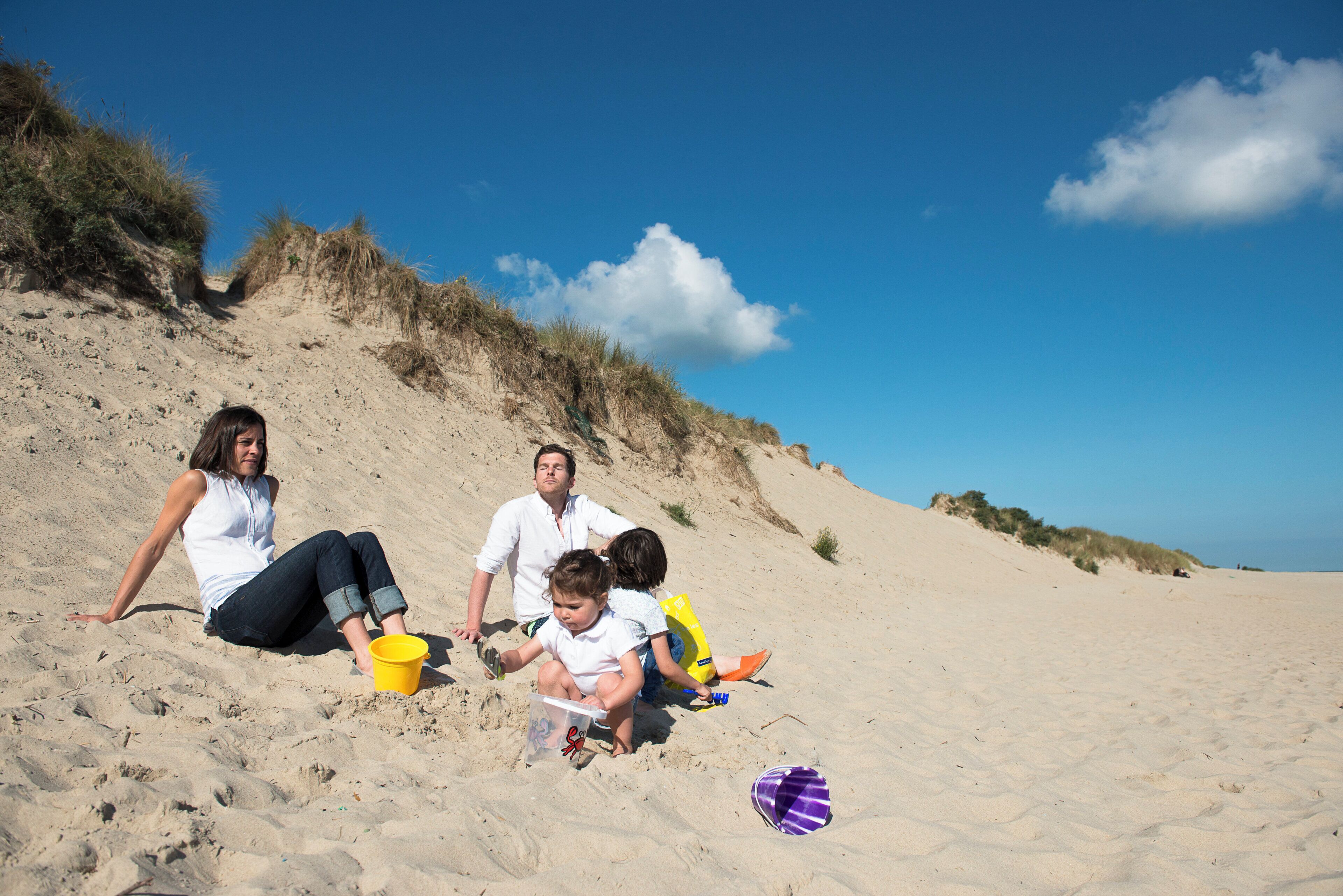 Ein Sandstrand mit Menschen, die sitzen und spielen.