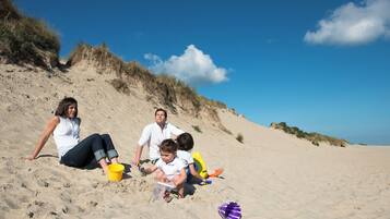 Ein Sandstrand mit Menschen, die sitzen und spielen.