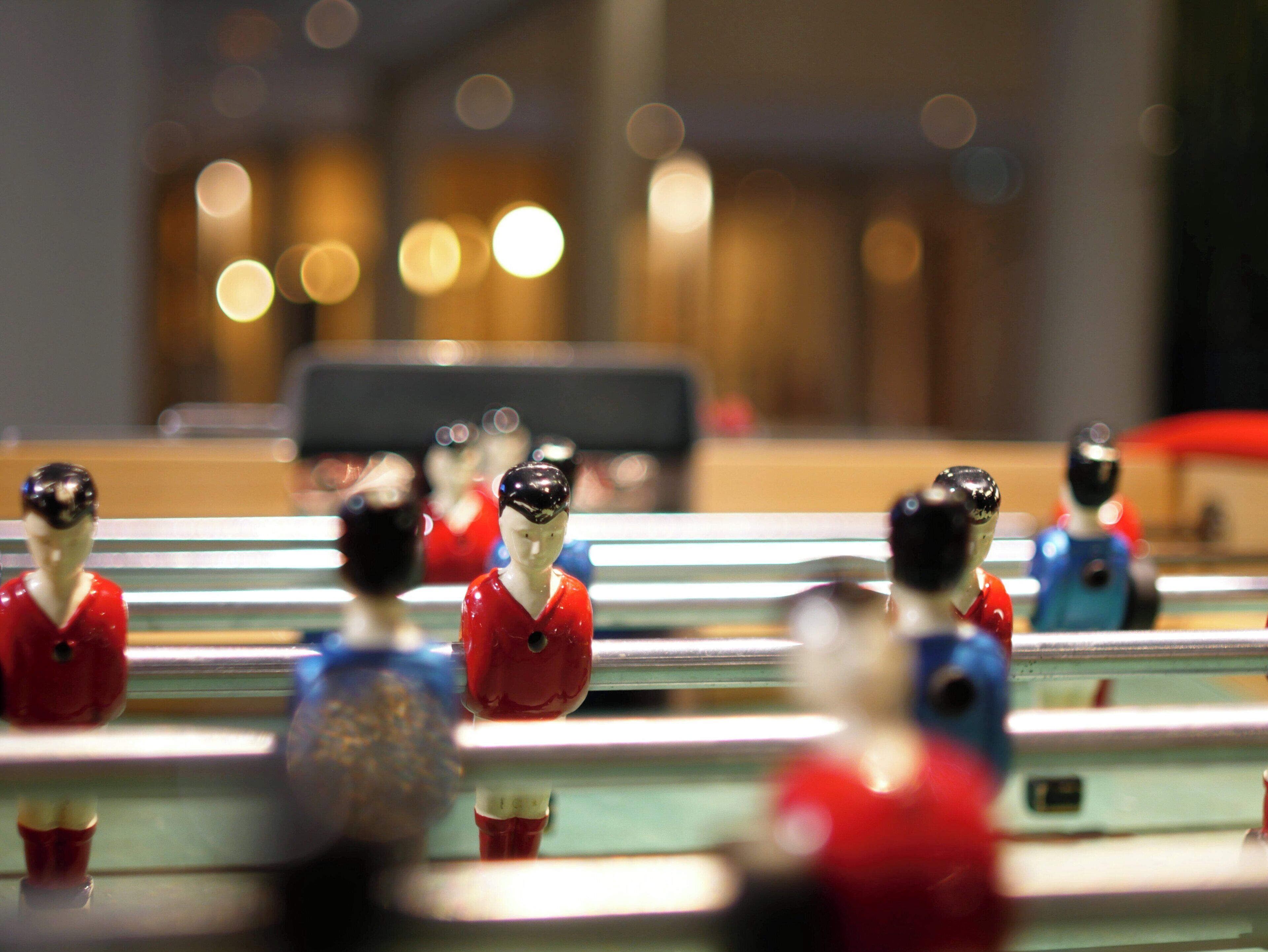 A close-up of a foosball table with figures in red and blue uniforms.
