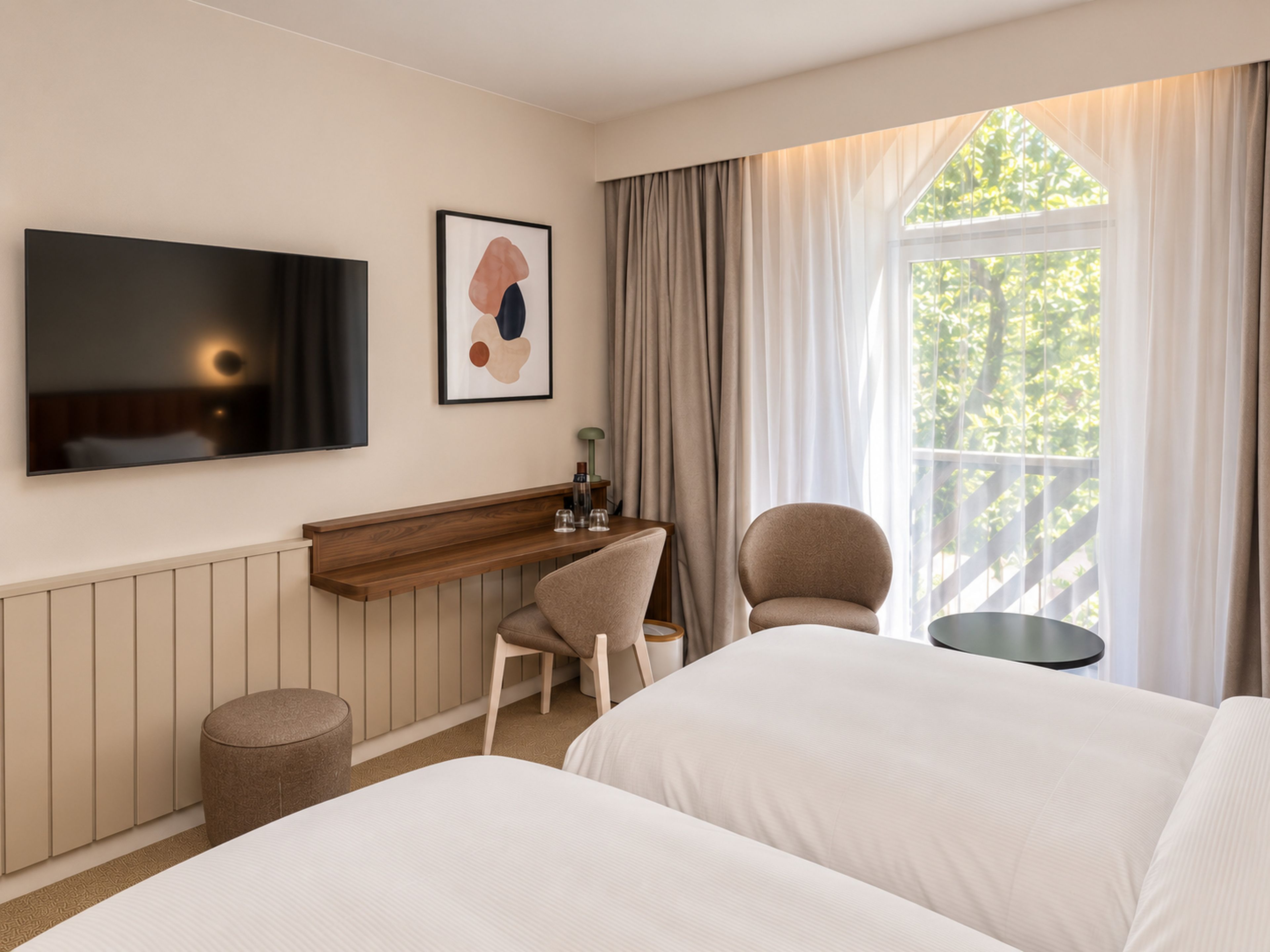 A hotel room with a bed, a desk, a chair, a TV, and a window with curtains.