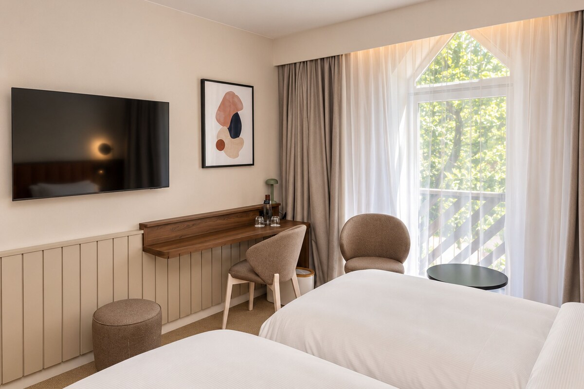 Een hotelkamer met een bed, een bureau, een stoel, een televisie en een raam met gordijnen.