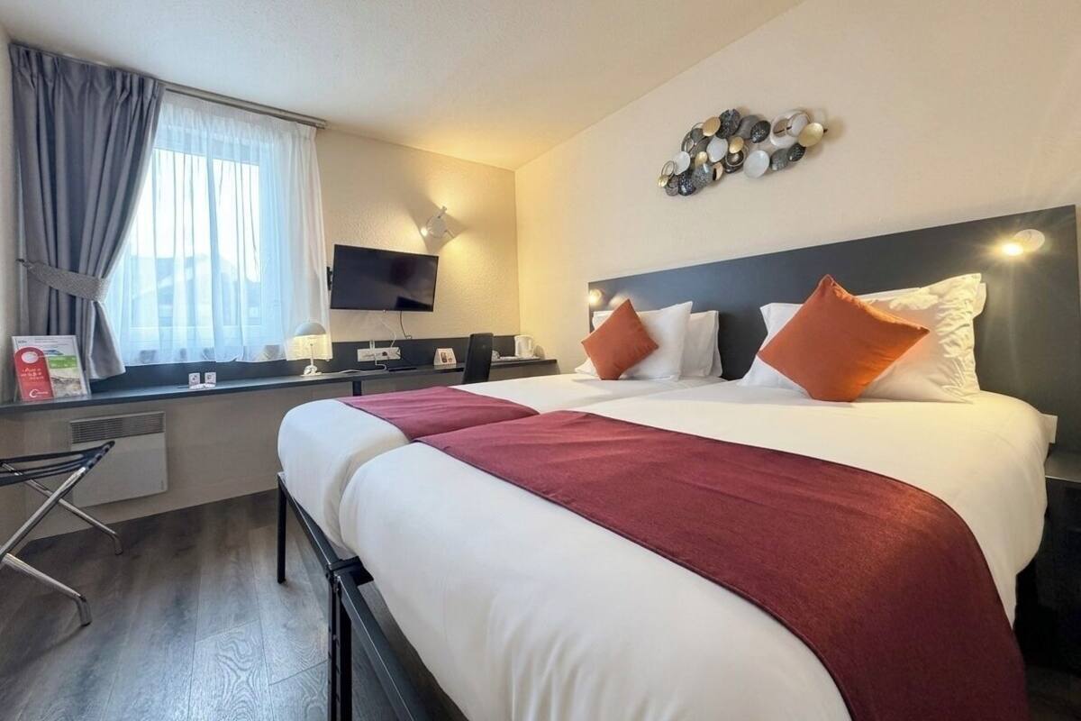 Een hotelkamer met een bed, een bureau, een televisie en een decoratie aan de muur.