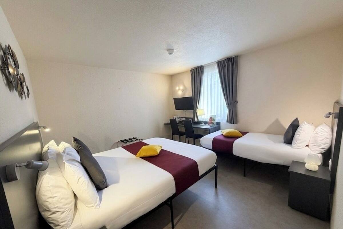 Een hotelkamer met twee bedden, een bureau, een stoel, een flatscreen televisie en een lamp.