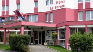 Un hôtel à la façade rouge et blanche, doté de grandes fenêtres et d’une entrée abritée.