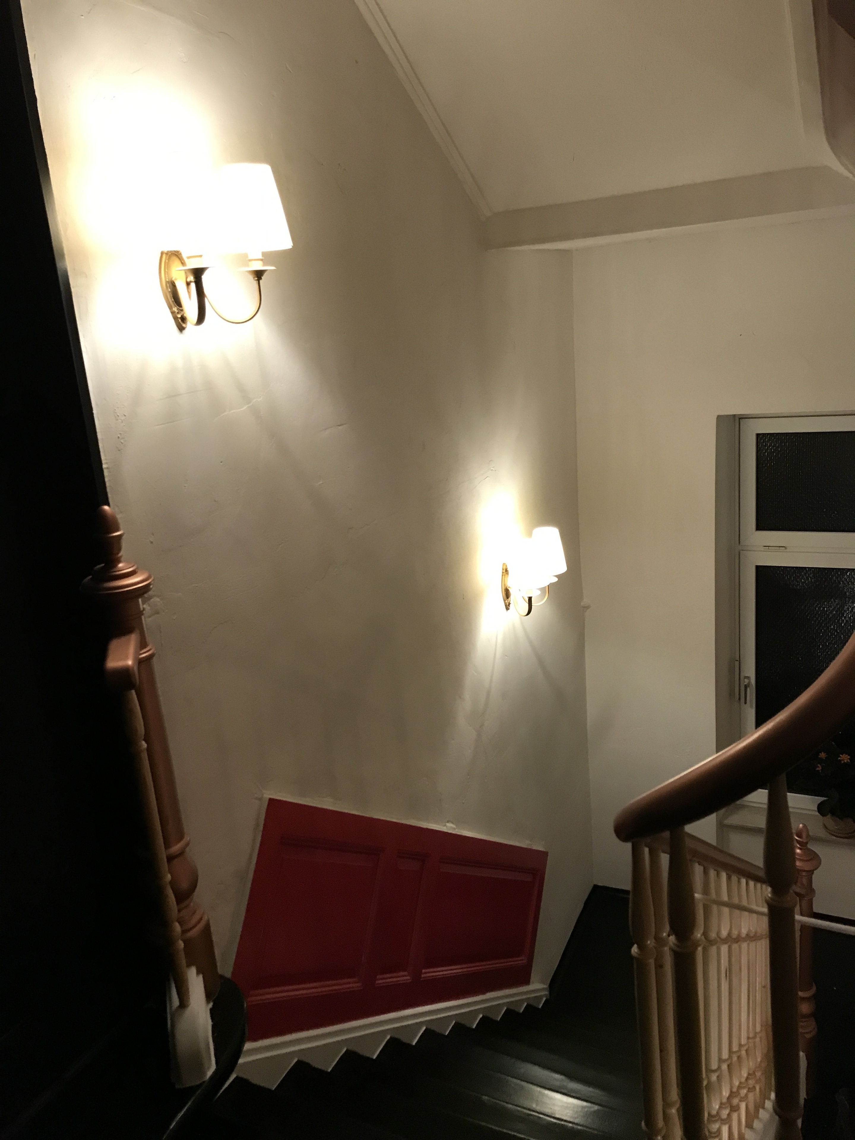 A staircase with wooden handrails and a red accent wall.
