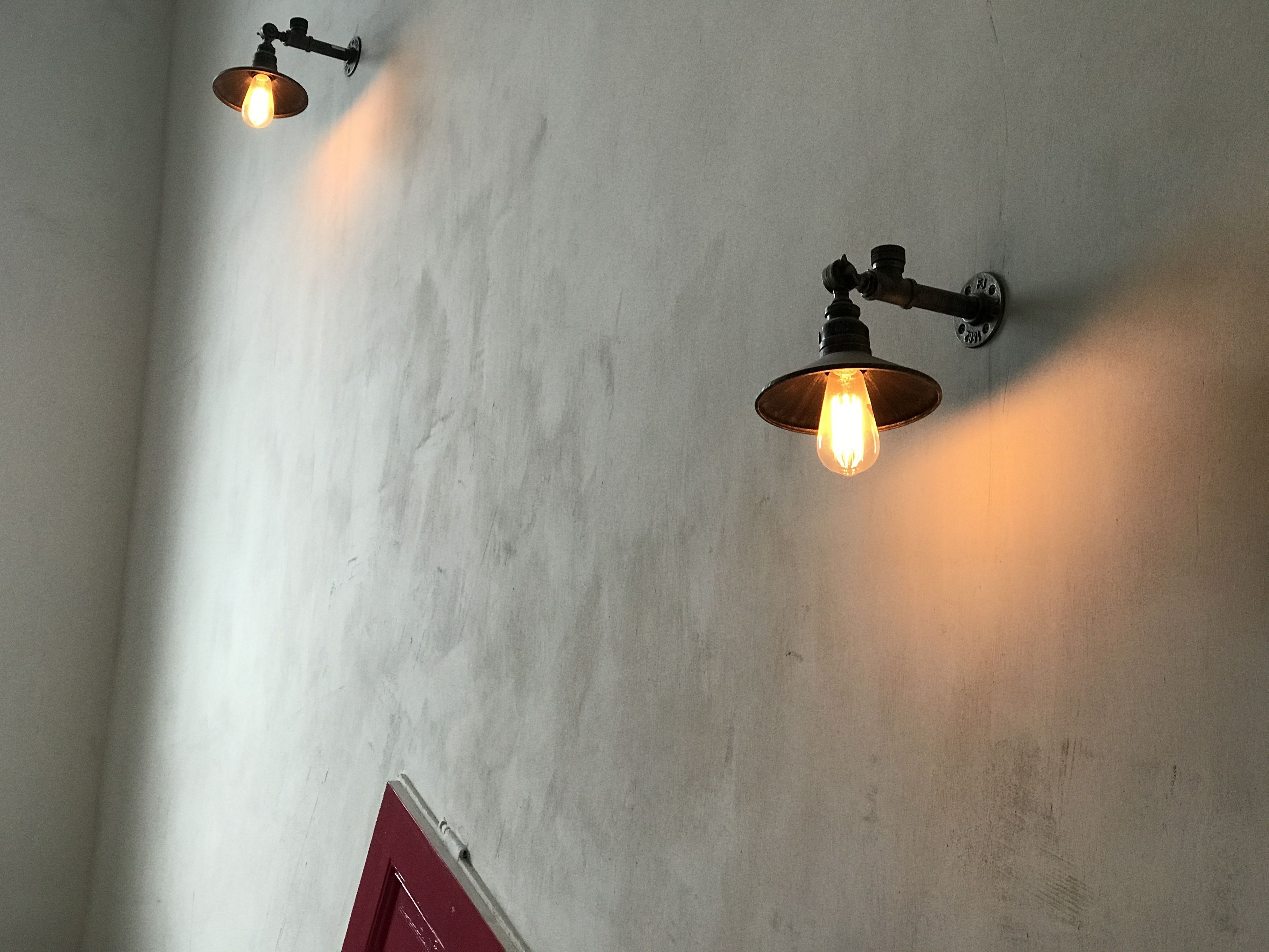 Two wall-mounted light fixtures with exposed bulbs on a plain wall.