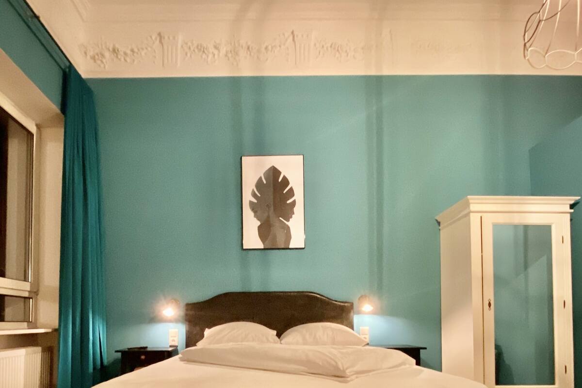 A bedroom with a bed, nightstands, a cabinet, and a wall art piece.