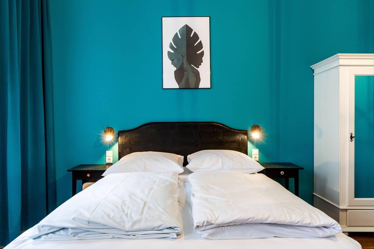 A neatly made bed with white linens, a dark headboard, and two bedside lamps.