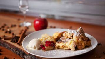 A plate with a dessert, an apple, and a glass of water on a wooden surface.