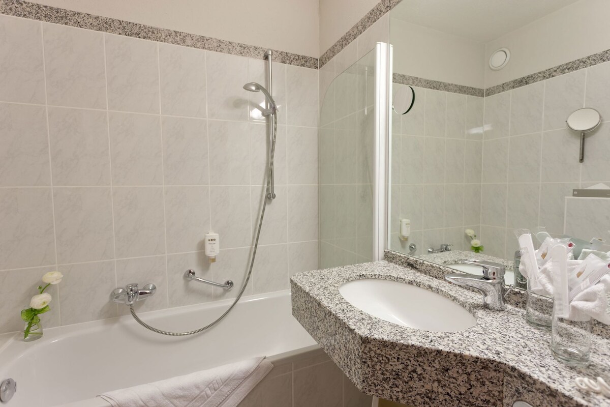 A bathroom with a bathtub, a shower, a granite countertop, a sink, and a mirror.