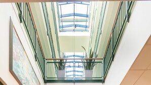Un hall d’hôtel avec un plafond en verre, un comptoir d’accueil et des chaises rouges.