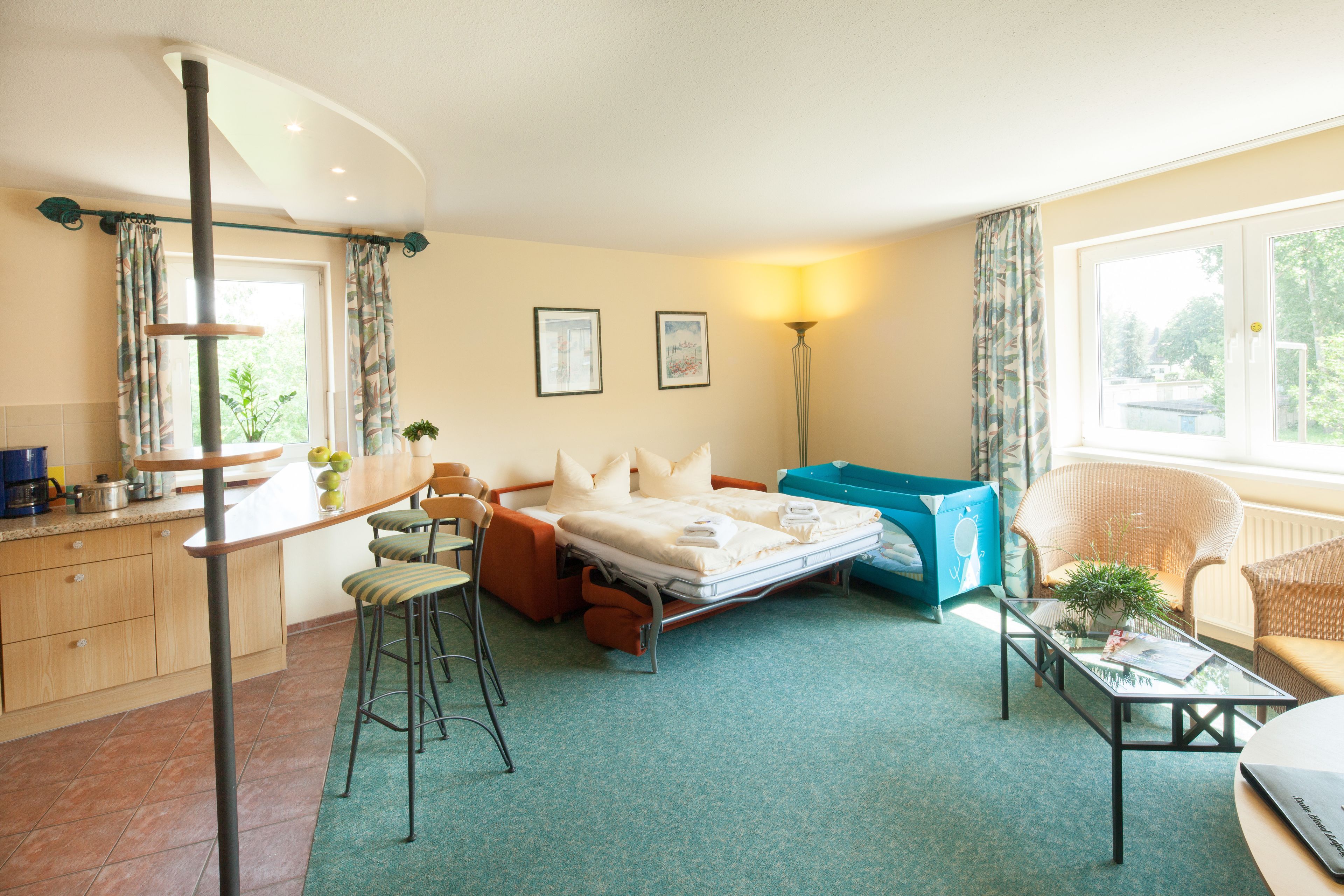 A compact hotel room with a bed, a small table, a chair, a sofa, a desk, and a window.