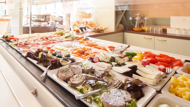 Un buffet proposant une variété de plats, notamment des viandes, des fromages et des légumes.
