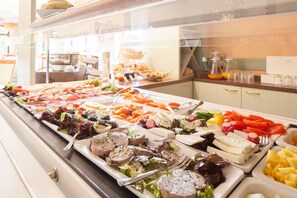 A buffet with various food items including meats, cheeses, and vegetables. - Suite Hotel Leipzig (Leipzig)