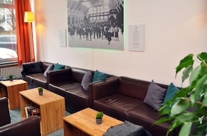 Een moderne lounge met lederen banken, houten tafels en een grote zwart-wit foto aan de muur.