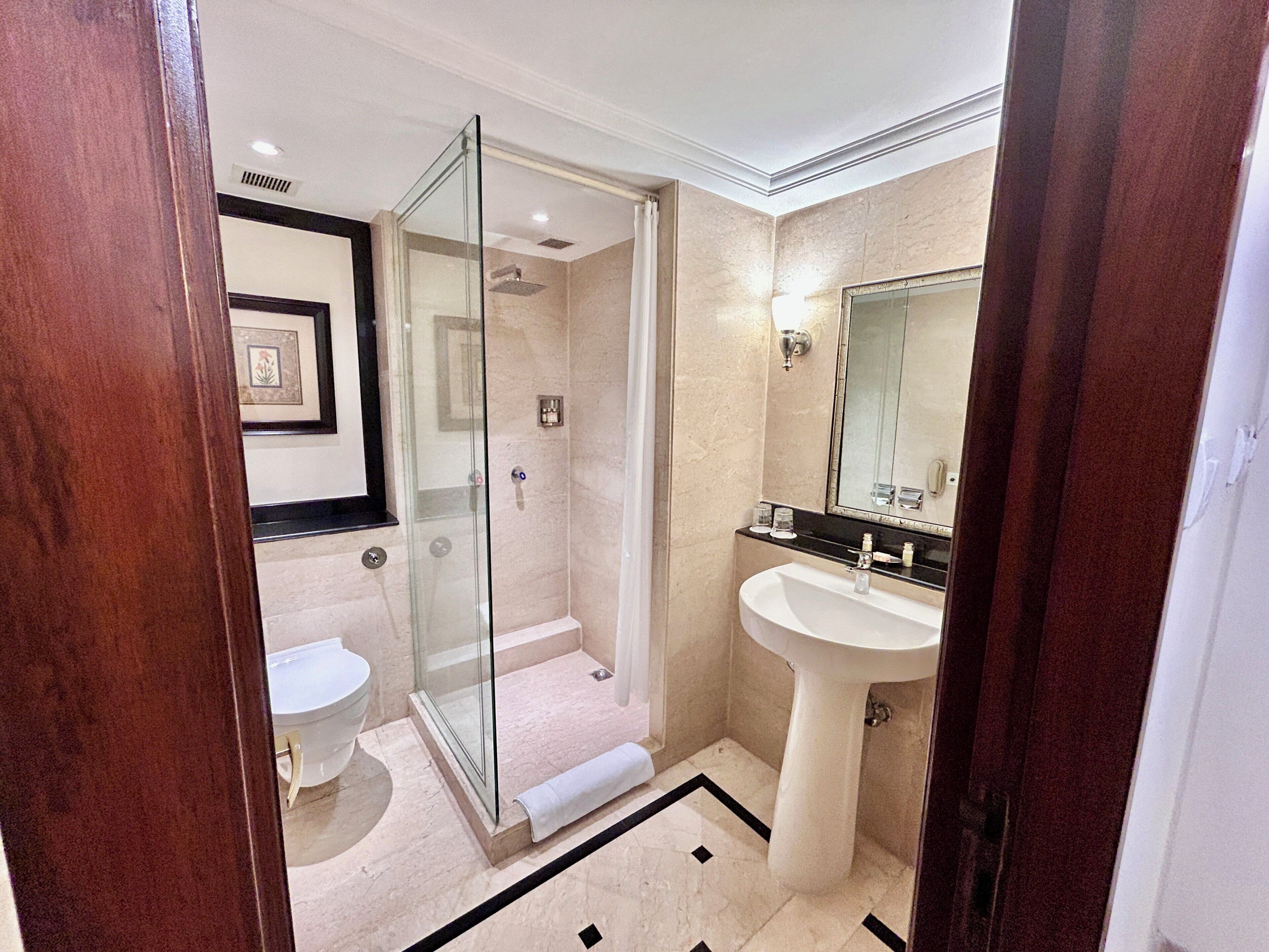 A bathroom with a glass-enclosed shower, a pedestal sink, and a toilet.