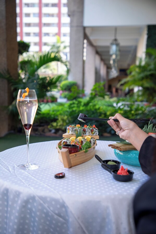 A table with a glass of wine, sushi, and chopsticks. - Eros Hotel New Delhi by IHG (New Delhi)
