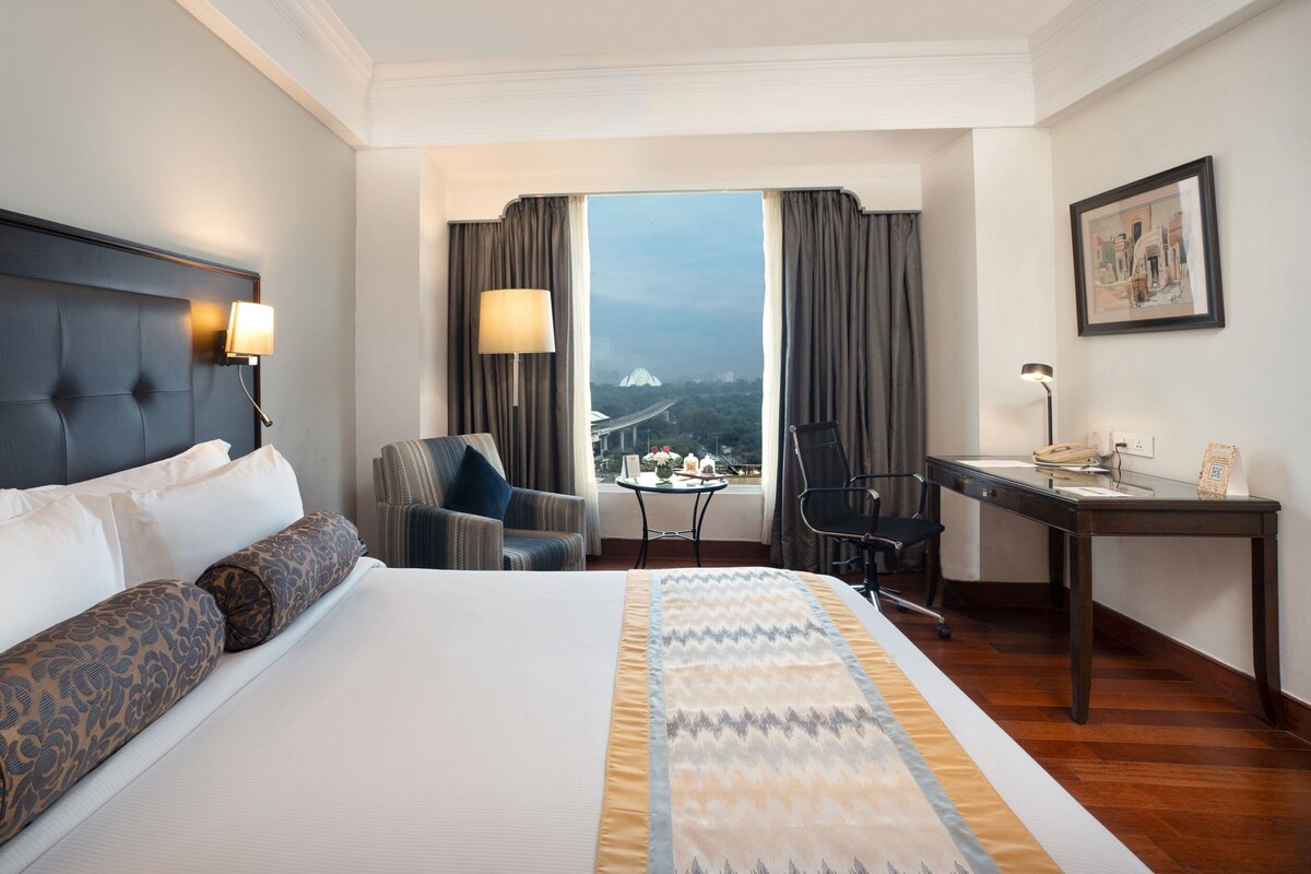Une chambre d’hôtel avec un grand lit, un bureau, une chaise et une vue sur un pont.