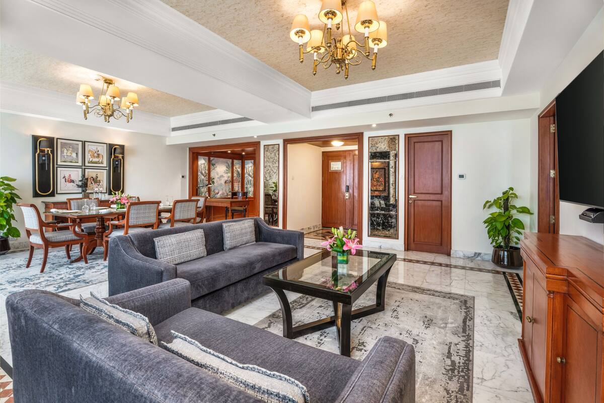 A spacious living area with a large sofa, a glass coffee table, and a chandelier.