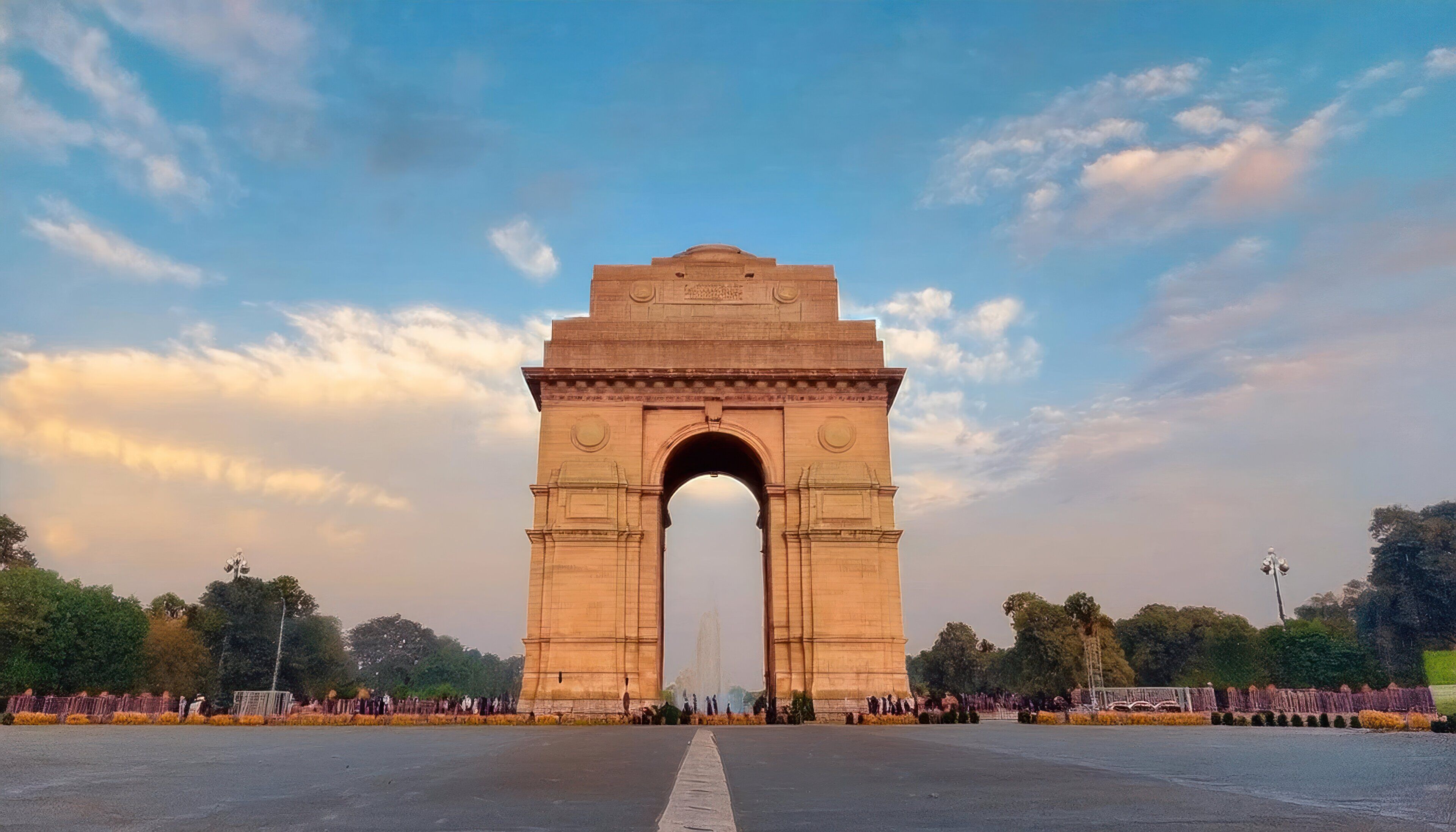 Un gran arco histórico con inscripciones, rodeado de un espacio abierto y árboles.