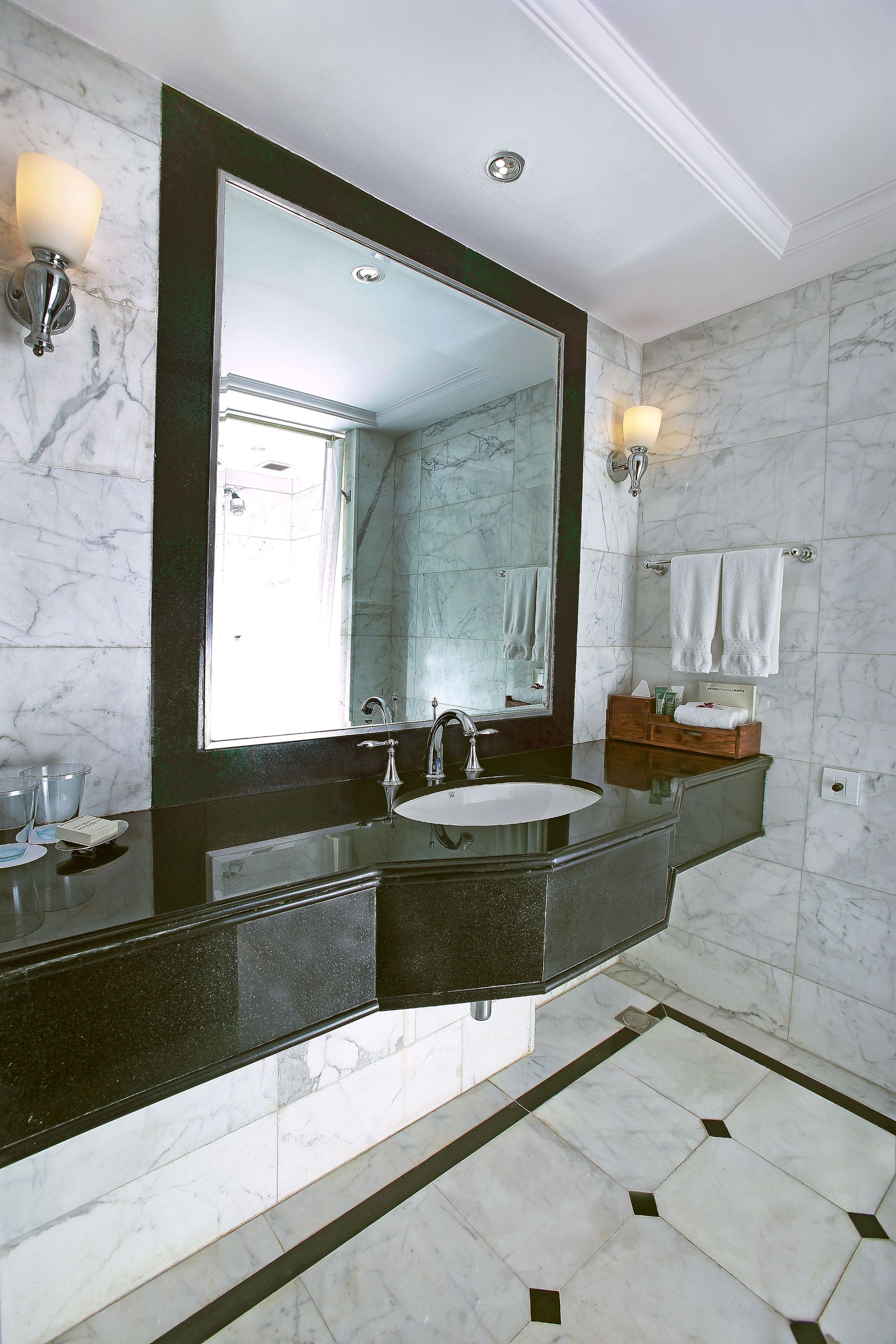 A bathroom with a large mirror, a sink, and two wall-mounted lights.