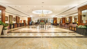 Un hall d’entrée spacieux, doté d’un sol en marbre, d’une composition florale centrale et d’un lustre.