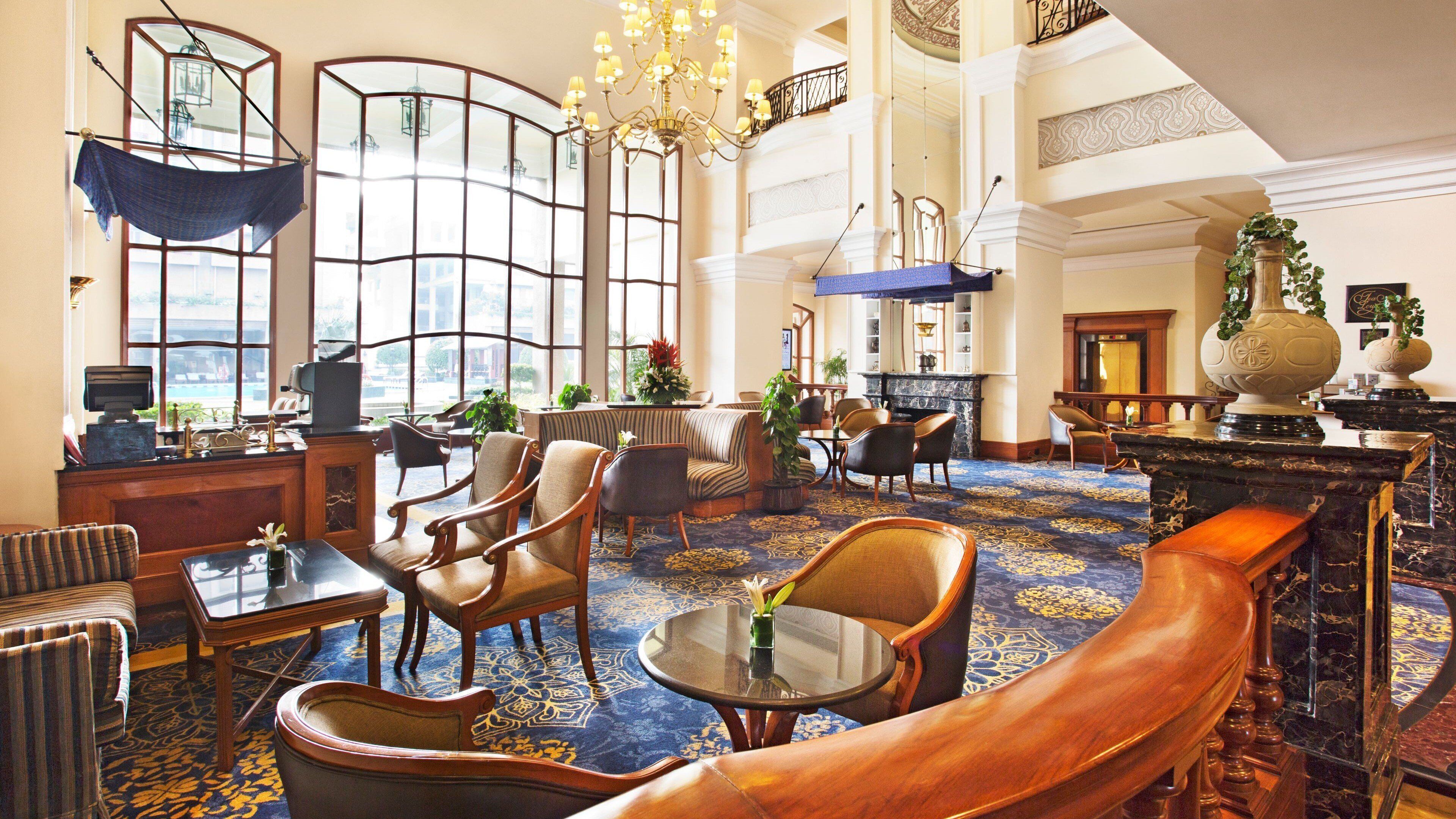 A spacious lobby with a high ceiling, large windows, and a variety of seating arrangements including sofas and chairs.