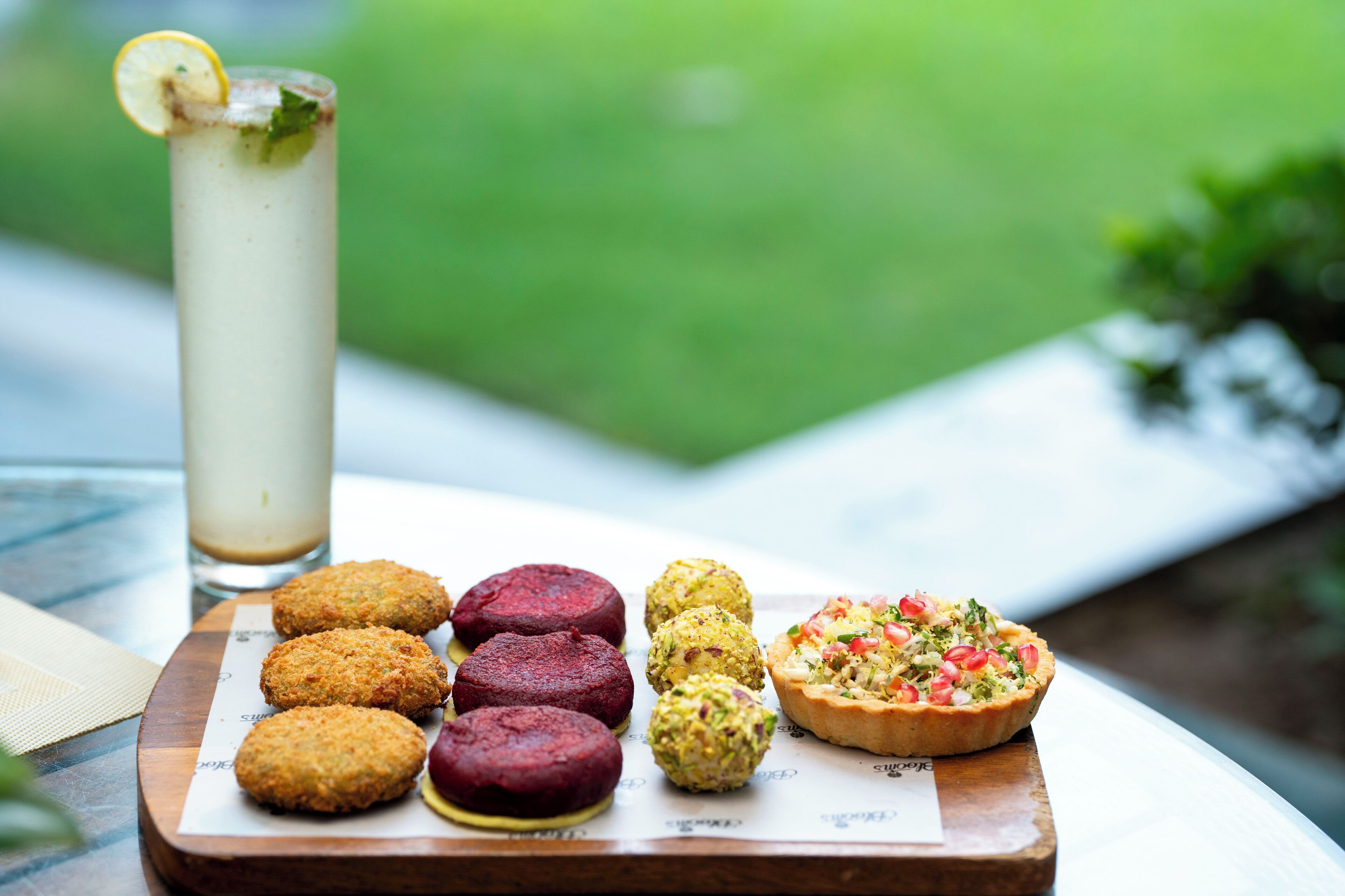A tray with various food items including fritters, a tall drink, and a tart.