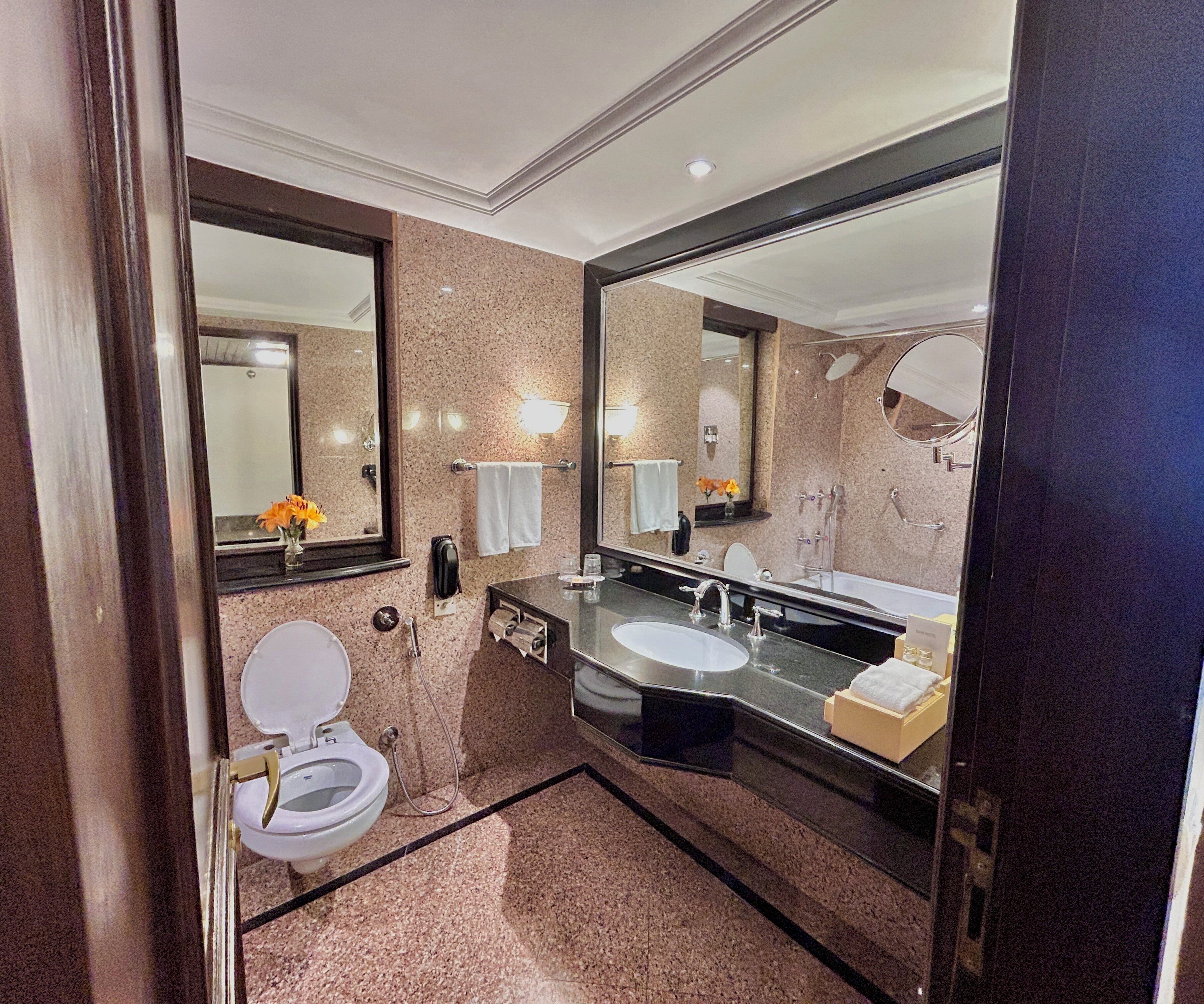 A modern bathroom with a toilet, sink, and large mirrors.