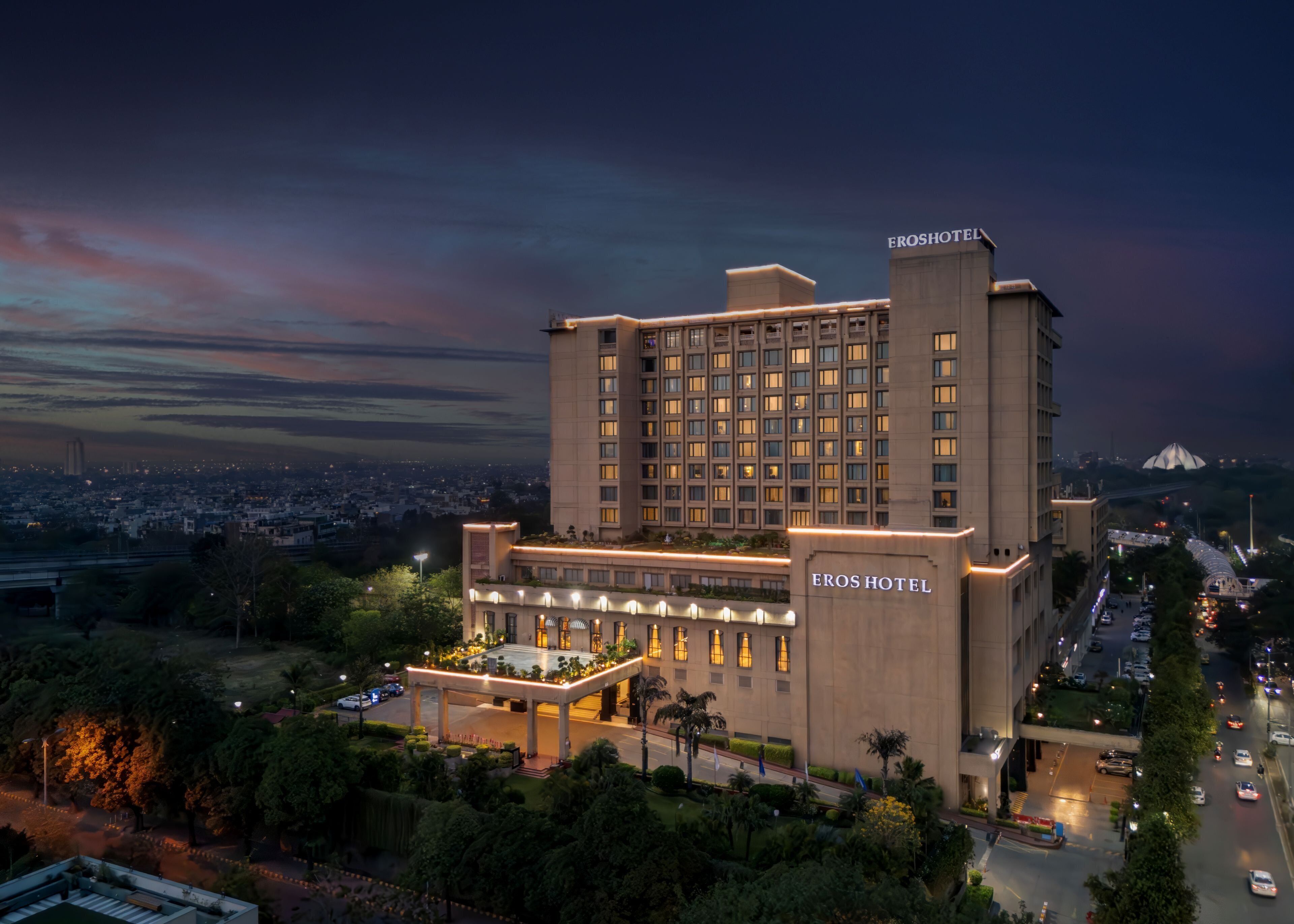 A large hotel with multiple floors, a prominent entrance, and a view of the cityscape in the background.