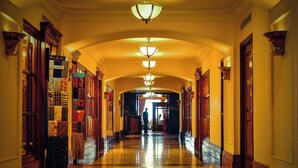 A long, polished hallway with a series of doors on either side, leading to a bright room at the end.