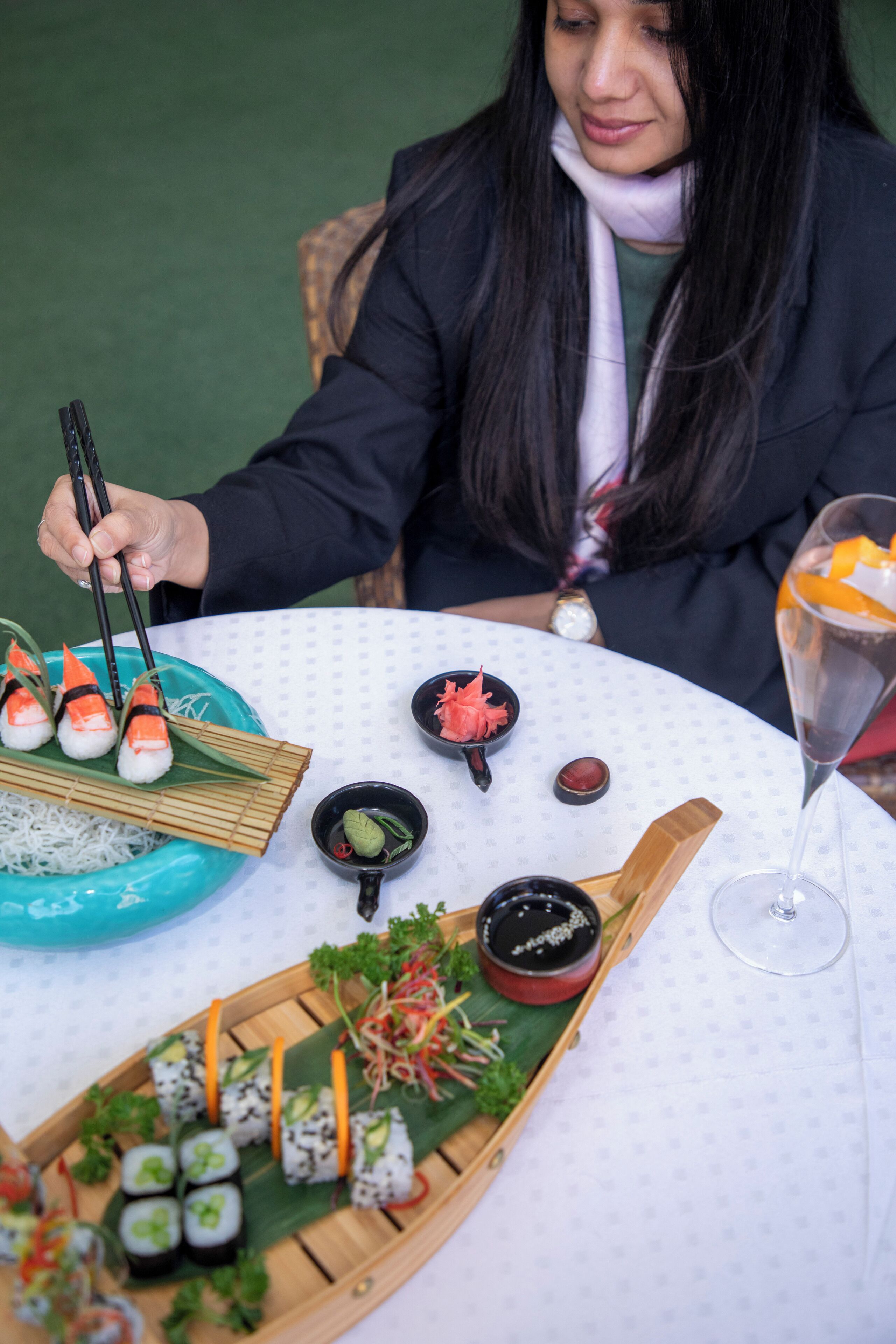 A table with sushi, a glass of drink, and a watch on the table.