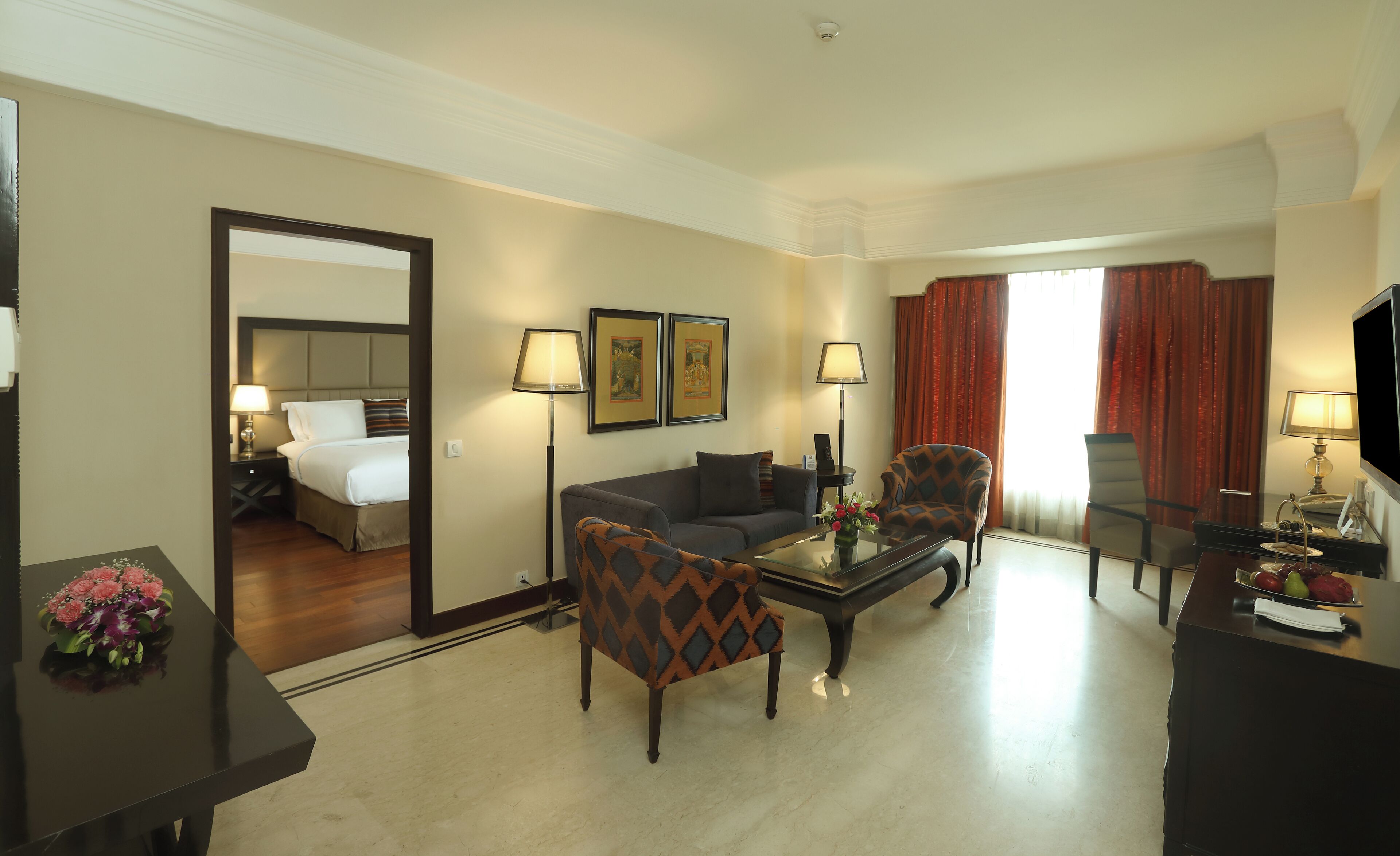 Una habitación de hotel con una cama, un sofá, una mesa de centro, una silla, un televisor y un escritorio con una lámpara.