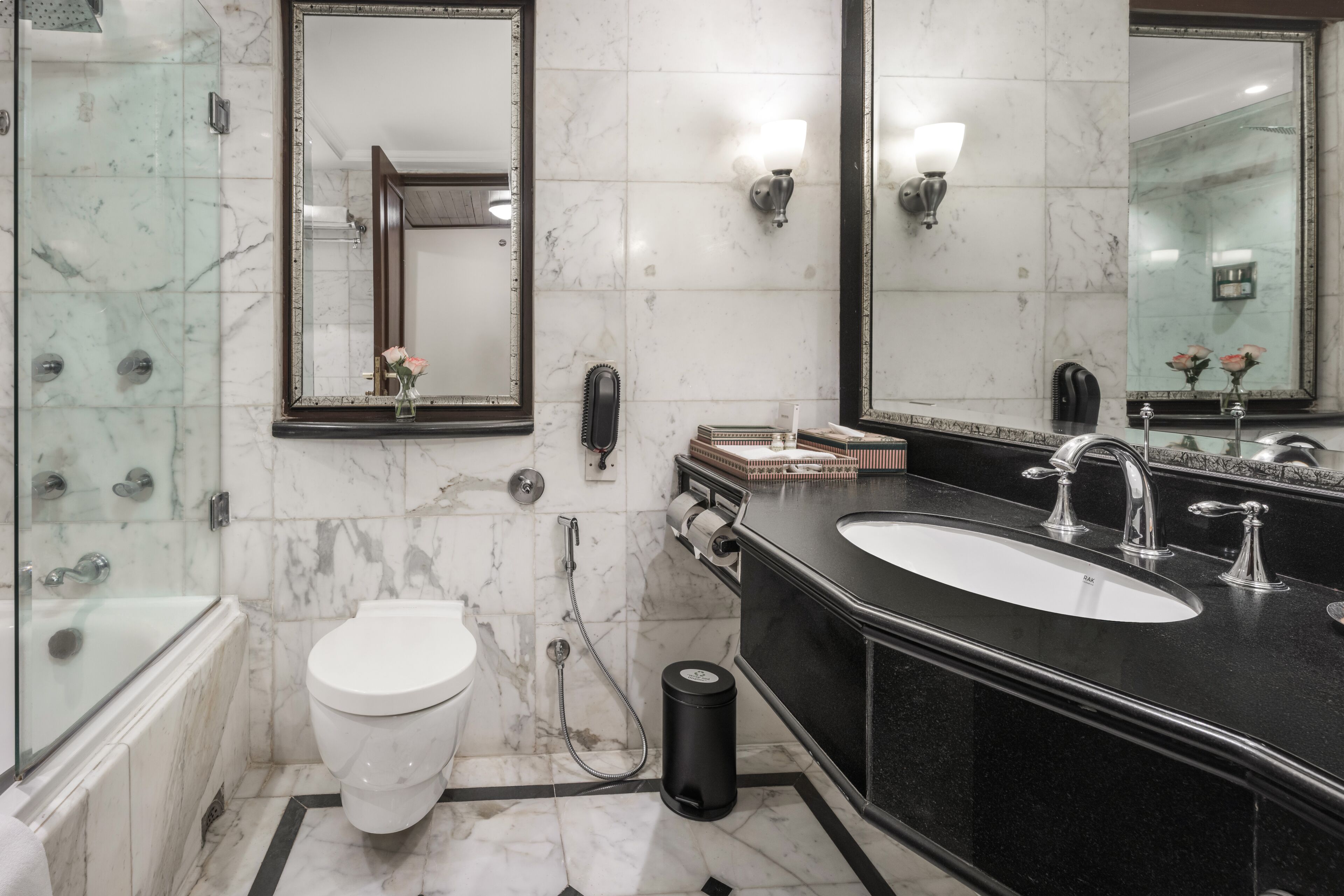 Un baño moderno con bañera, inodoro, lavabo y dos espejos.