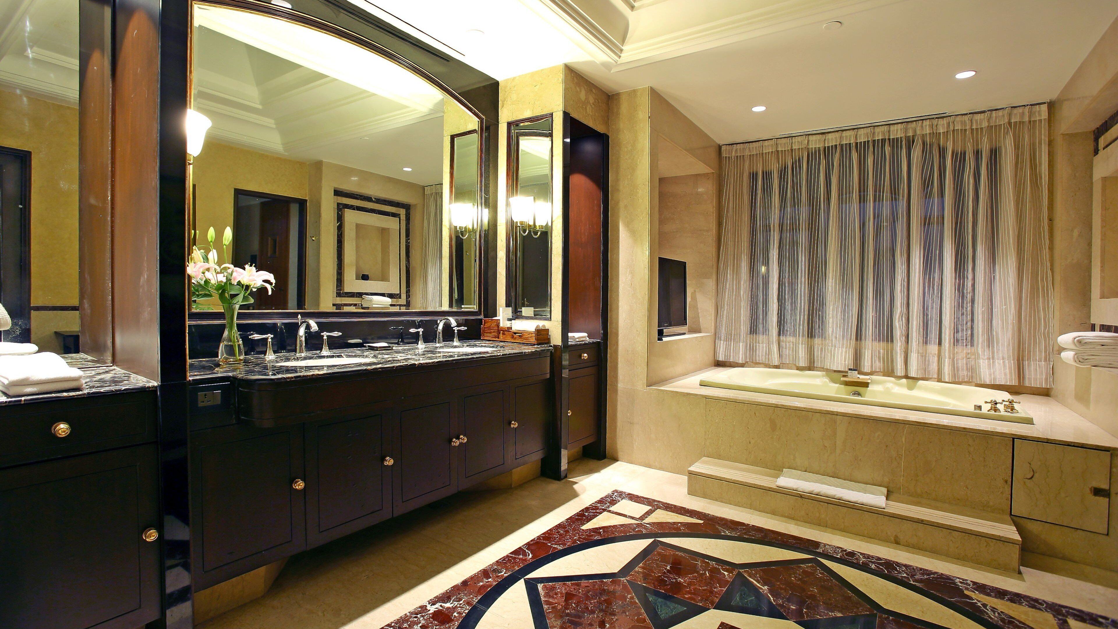 A bathroom with a double sink vanity, a large mirror, and a patterned floor.