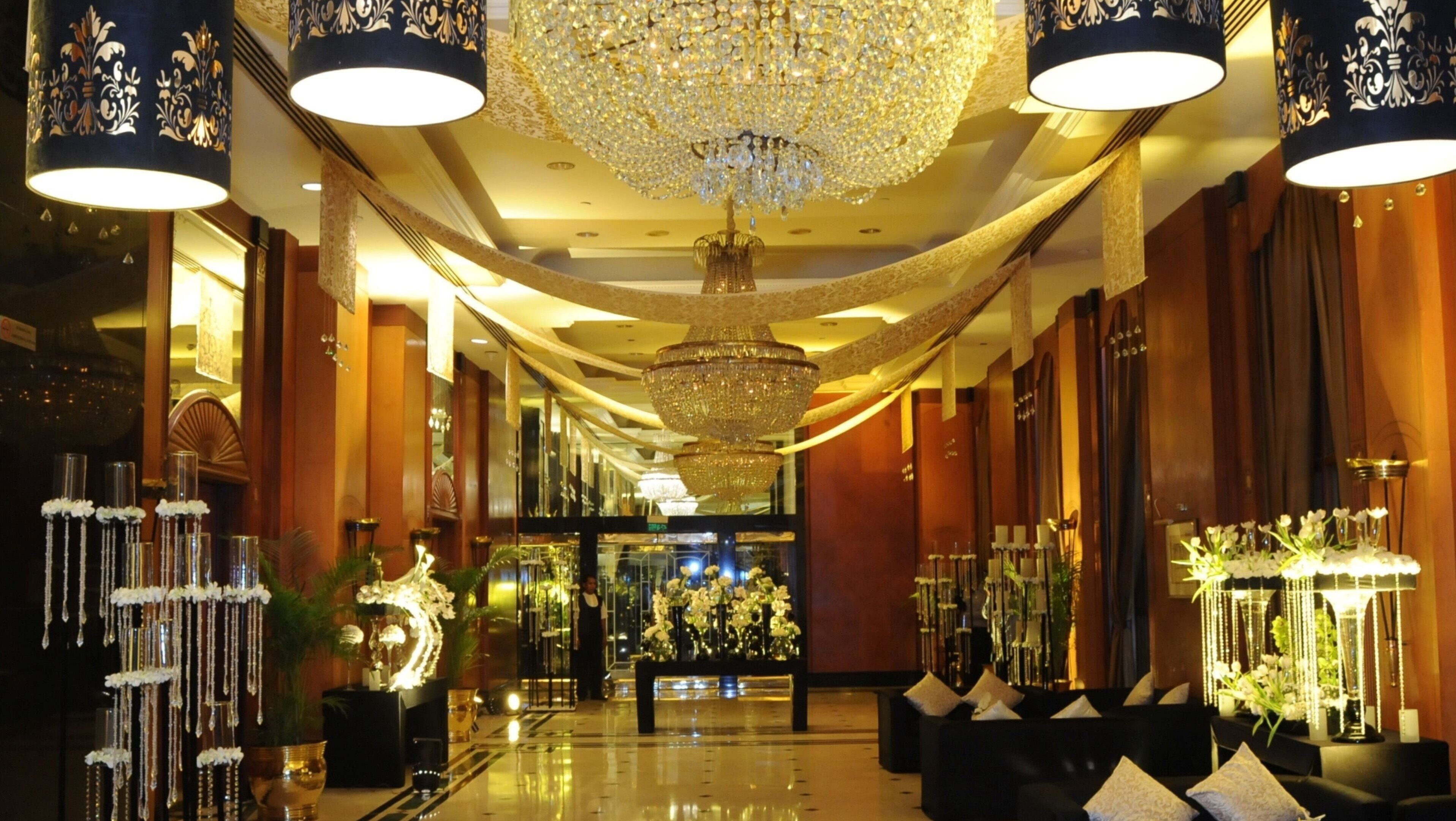 A luxurious hotel lobby with chandeliers, elegant decor, and a polished floor.
