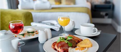 Un desayuno con huevos, tocino y tostadas, un vaso de zumo de naranja y un vaso de vino tinto.