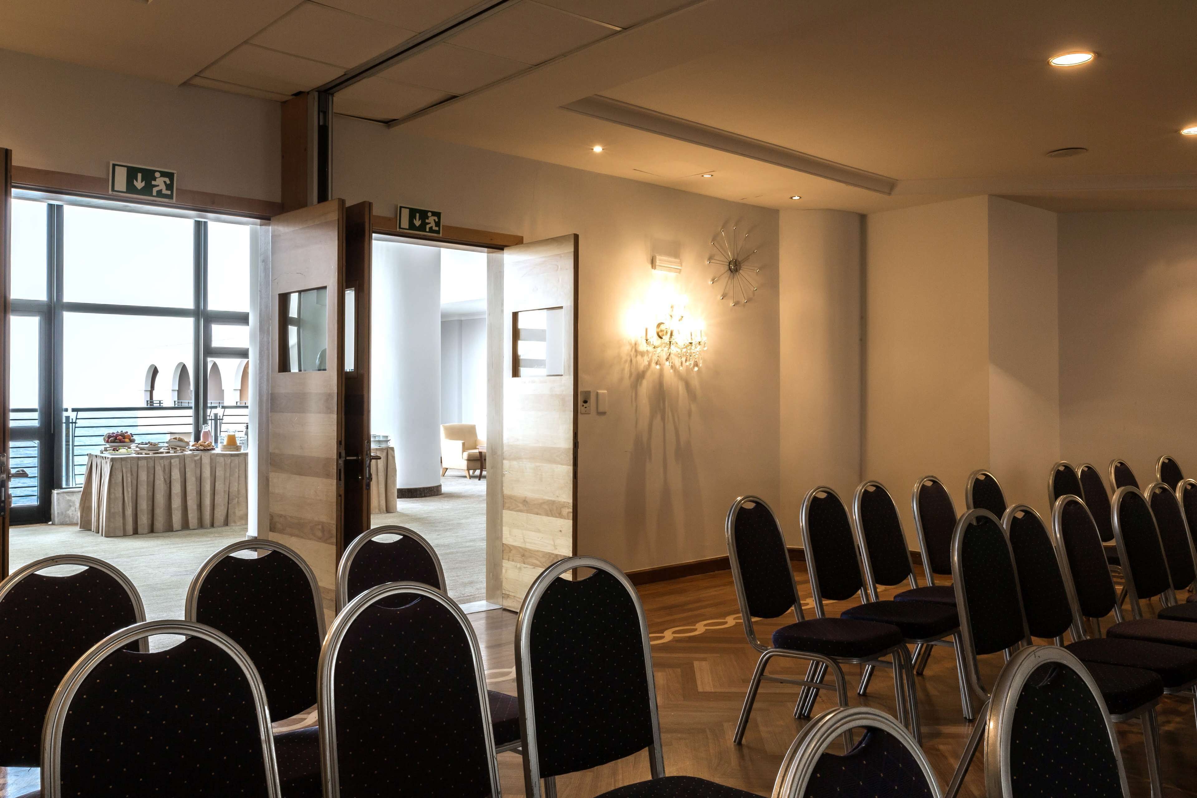 A conference room with rows of chairs, a chandelier, and a view of the outdoors.