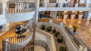 A multi-level hotel lobby with a marble staircase, potted plants, and a reception desk. - Radisson Blu Resort, Malta St. Julian's (St. Julian's)