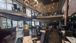 A multi-level restaurant with a bar area, dining tables, and a staircase. - Radisson Blu Resort, Malta St. Julian's (St. Julian's)