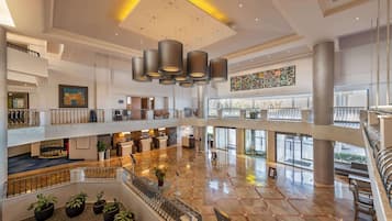 A spacious, multi-level lobby with a modern design, featuring a central open area, multiple floors, and a reception desk.