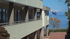 Een modern gebouw met een balkon dat uitkijkt over een wateroppervlak en een vlag.