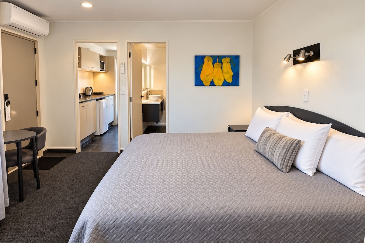 Une chambre d’hôtel avec un lit, un bureau et une kitchenette.