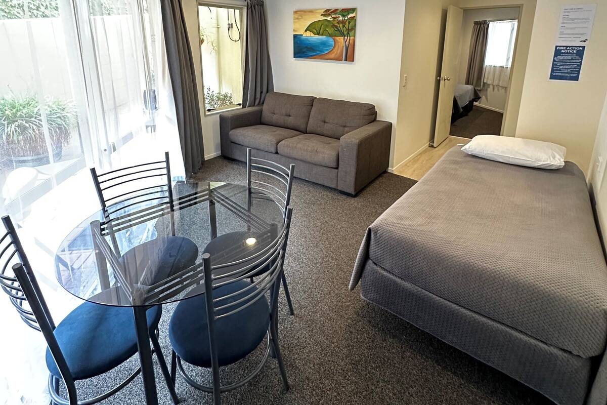 Une pièce comprenant un lit, un canapé, une table à manger avec des chaises et un tableau accroché au mur.