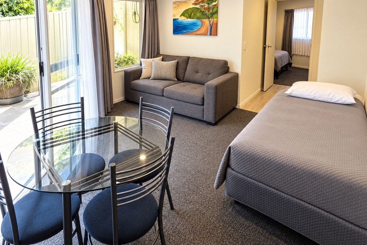 Une pièce comprenant un lit, un canapé, une table à manger avec des chaises et un tableau accroché au mur.