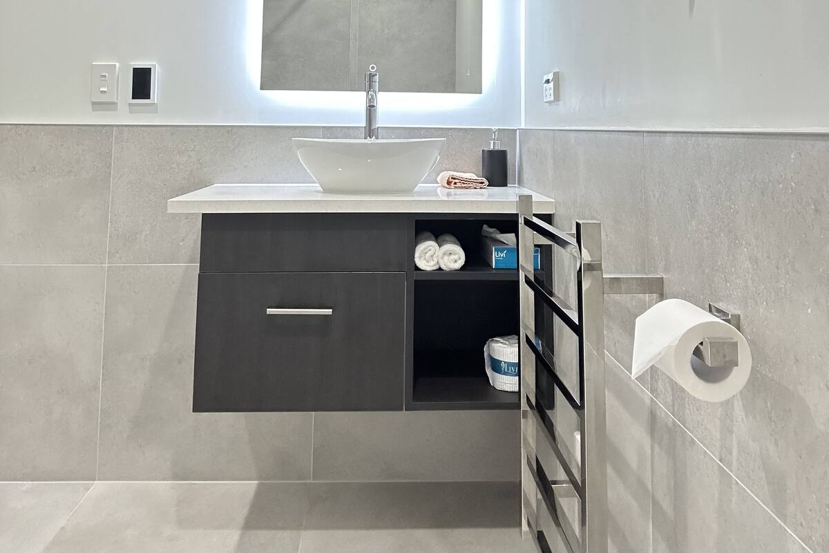 Une salle de bain moderne avec un lavabo intégré, un miroir et une douche.