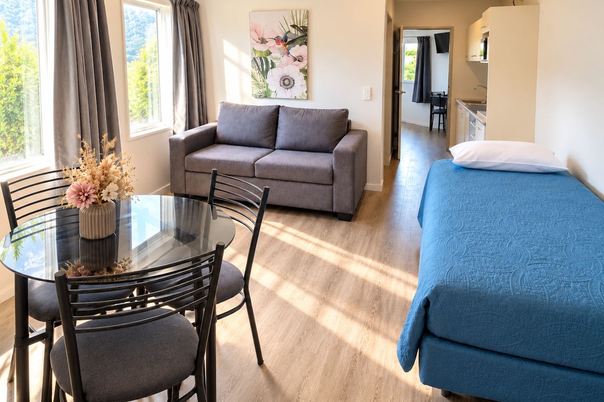 Une pièce comprenant un canapé, un lit, une table à manger avec des chaises et un tableau accroché au mur.